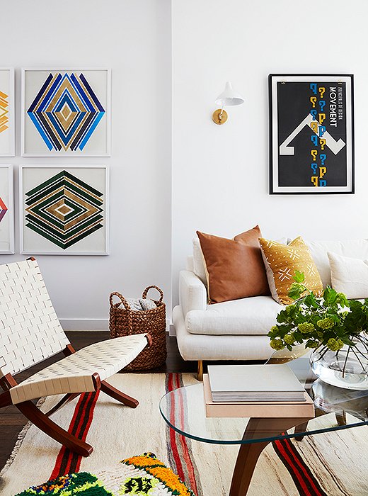 It’s on the left side of this wall where we discover Mindy’s penchant for bling. Custom graphic prints by Wonderwall feature the space’s token touches of blue and green, atop which layers of gold leaf shine. Above the sofa, sconces by AERIN flank another punchy piece.
