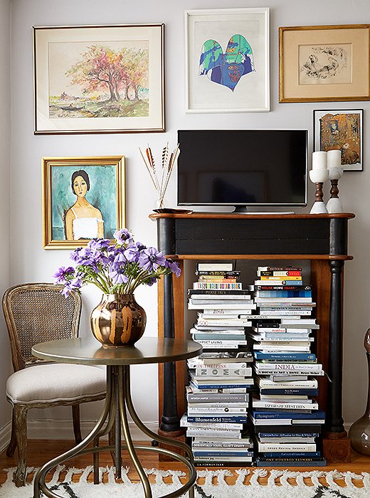 A vintage bistro table serves as Ari’s worktable, dinner surface, and bar when hosting friends; Anthony brought in an ornate wood mantel that elevates the TV while holding Ari’s books.
