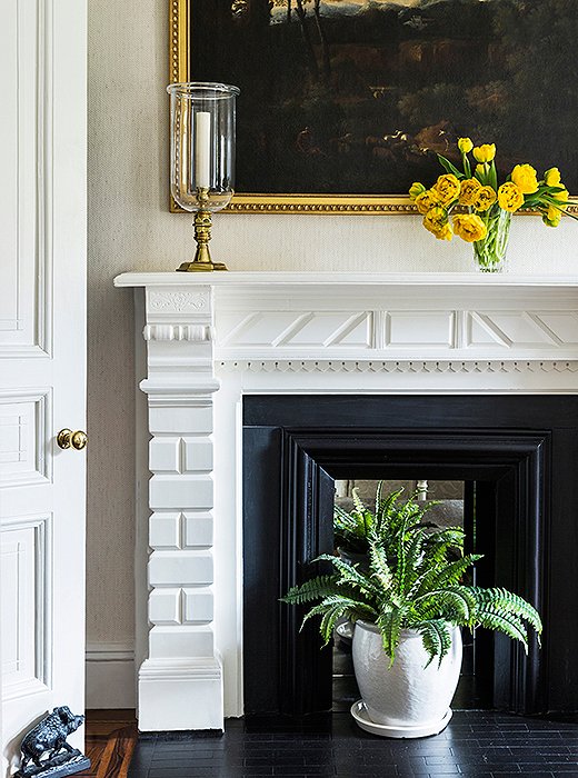 Above the fireplace, a classic landscape gives CeCe’s bedroom a pastoral view—and lends a touch of color to the monochromatic scheme.
