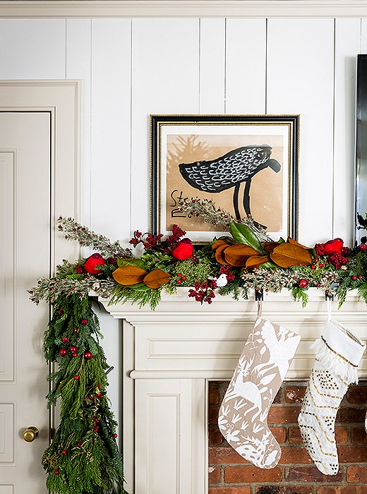 A red cardinal perches between red berries and a magnolia branch in this charming woodland vignette. 
