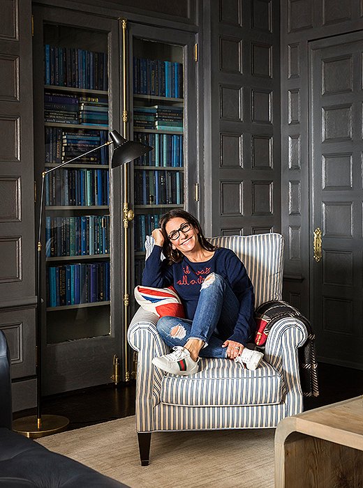 Bobbi Brown kicks back in Gucci sneakers and a Lingua Franca sweater beside a midcentury-style lamp by AERIN. 

