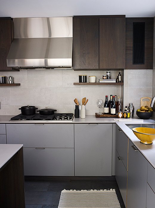 The couple kept things streamlined in the kitchen with the help of the design firm Henrybuilt. Upper cabinets in dark wood lend warmth to the otherwise gray palette. 
