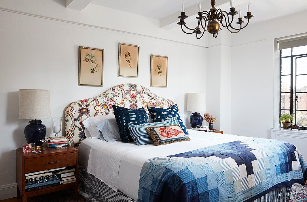 In the bedroom, a trio of Audubon prints crowns an upholstered headboard. Indigo pillows and a patchwork throw offer as much comfort as the tarnished chandelier does tradition.
