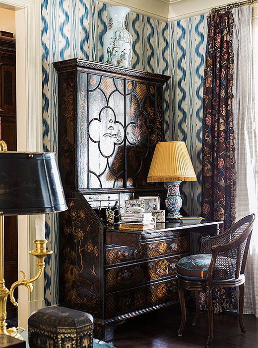 A secretary desk embellished with chinoiserie motifs hosts a lamp that was once a vase. Silver accents and stacks of books transform this simple “station” into a vignette. 
