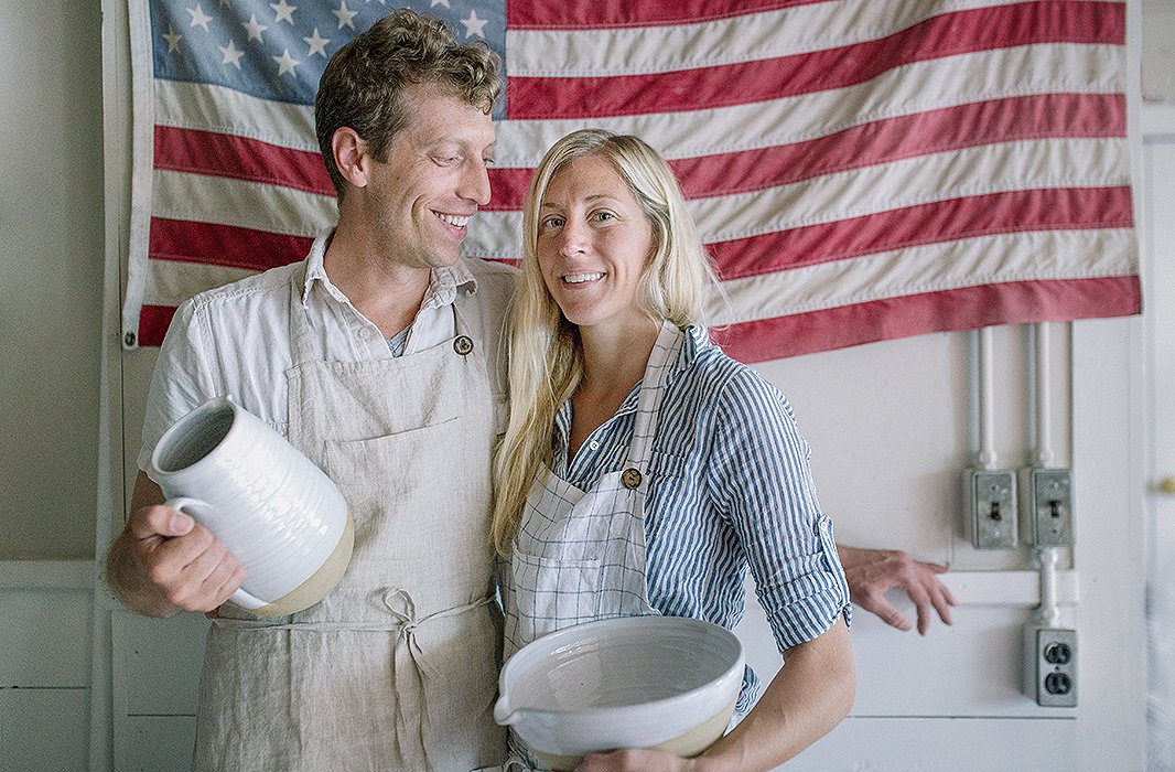 Founders James and Zoe Zilian in Farmhouse Pottery’s Woodstock, VT, studio, holding the Farmer’s Pitcher and Pantry Mixing Bowl. 
