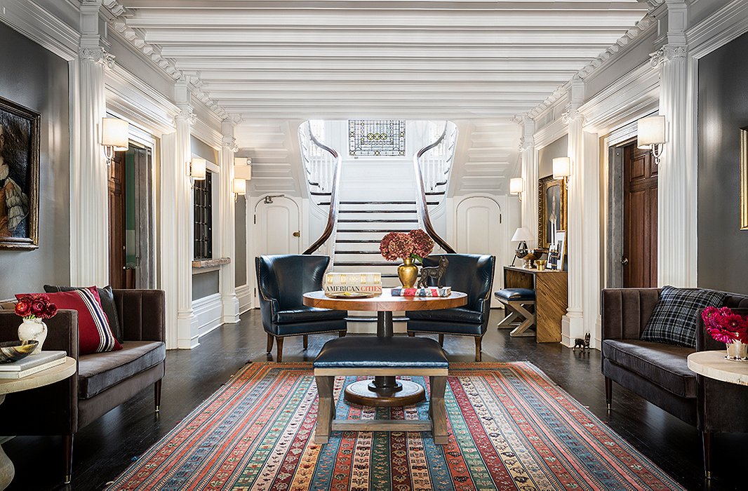 A pedestal table by Noir flanked by a pair of leather wingbacks and a navy leather ottoman by Brownstone Upholstery form a focal point in The George’s lobby. A patterned rug adds depth and definition to the expansive space. 
