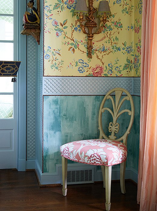 Trimmed wallpaper, a gilded sconce, and silk drapes create grandeur in a far corner.
