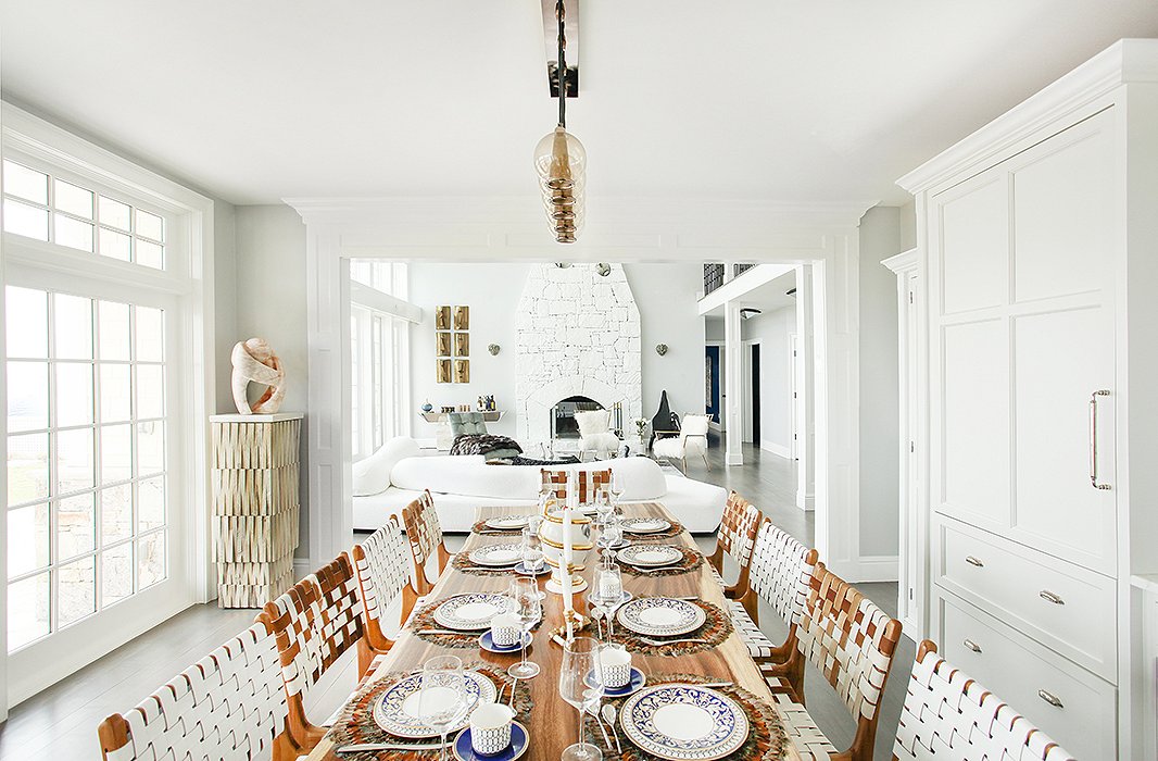 Set just off an open-plan kitchen, the dining space features a table topped with an Indonesian walnut slab surrounded by chairs in woven leather. To the left, a pedestal constructed of untreated wood hosts a pink marble sculpture. “The tones of all the pieces reflect those you’d find outside,” notes Sasha, “and add a feeling of warmth to the whole room.”
