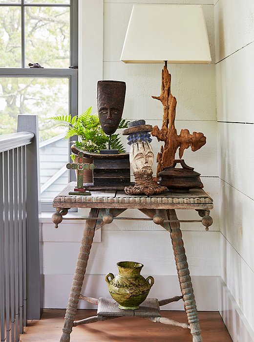 African masks and a lamp crafted from a sculptural piece of driftwood form a well-collected vignette atop a spindle-leg table. T.R. picked up the green ceramic vessel at a souk in Marrakech.
