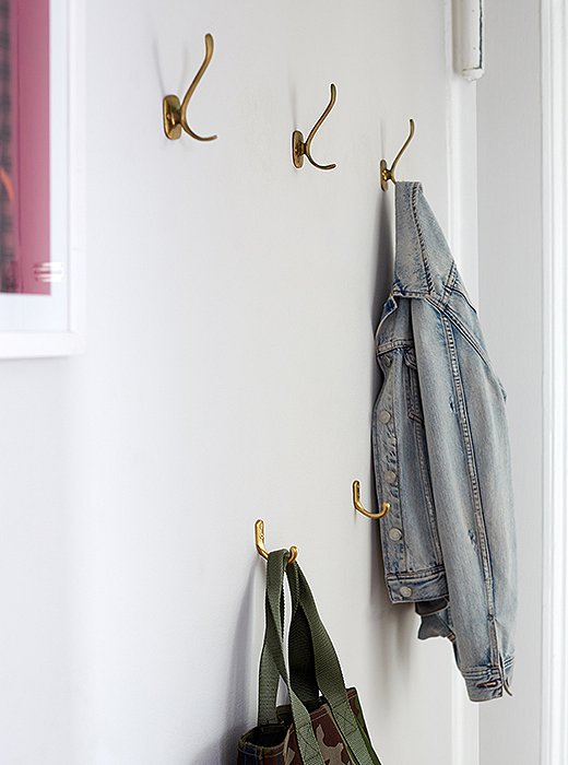 A double row of vintage hooks lets Ari hang her coats above and her totes and bags below.
