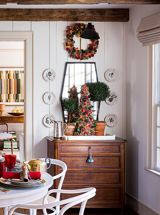 A kitchen corner gets merry with a miniature beaded-fruit tree and matching wreath—both selected to tie into the red, green, and gold scheme. 
