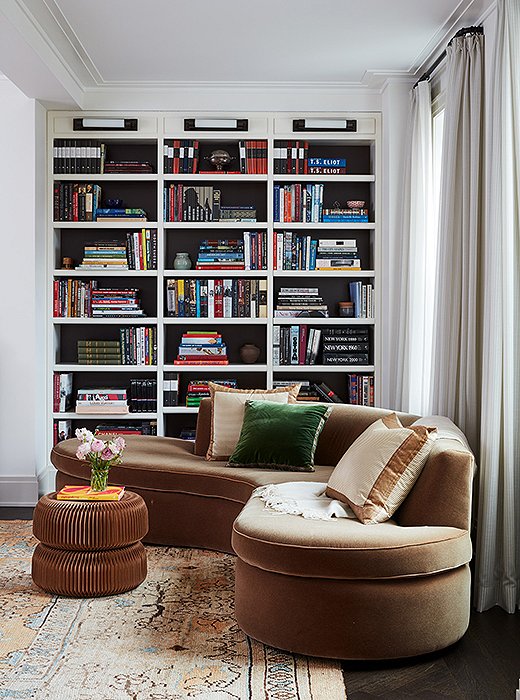 The designers had the back of these built-in bookshelves painted black—a simple trick that helps visually ground the room and allows the objects on display to really pop.

