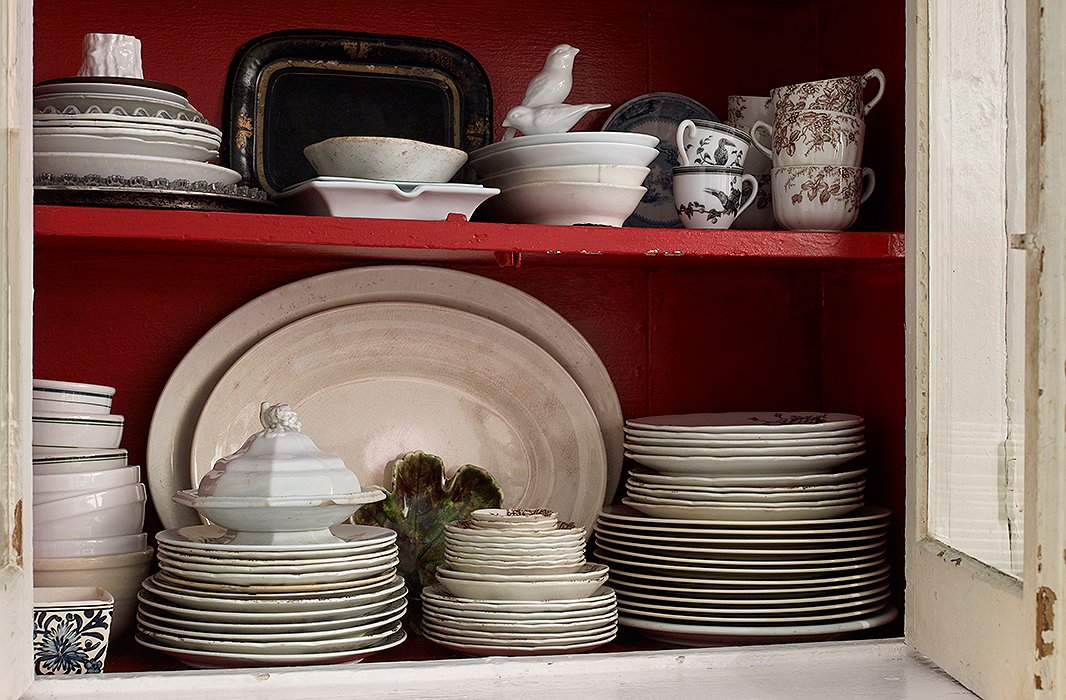 Original to the apartment, a delightfully dilapidated kitchen cabinet—which Michael customized with a coat of Glidden’s Candy Apple—displays vintage dishes, cups, and serveware too beautiful to hide. 
