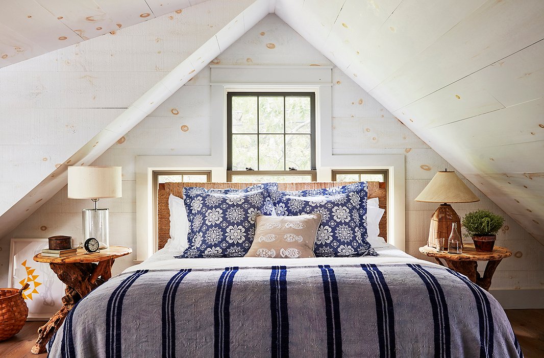Nightstands found at the Brimfield Antique Show flank a woven-rush headboard in a cozy guest bedroom. The pine-clad walls were washed with milk paint, which “added a great textural quality,” says T.R. 
