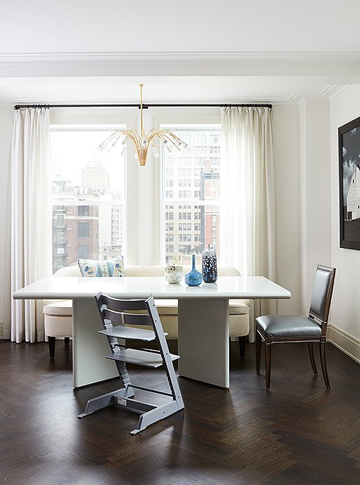 Modern meets traditional in the dining area, where a Louis XVI-style chair and a graceful settee nestle up to a sleek contemporary table.
