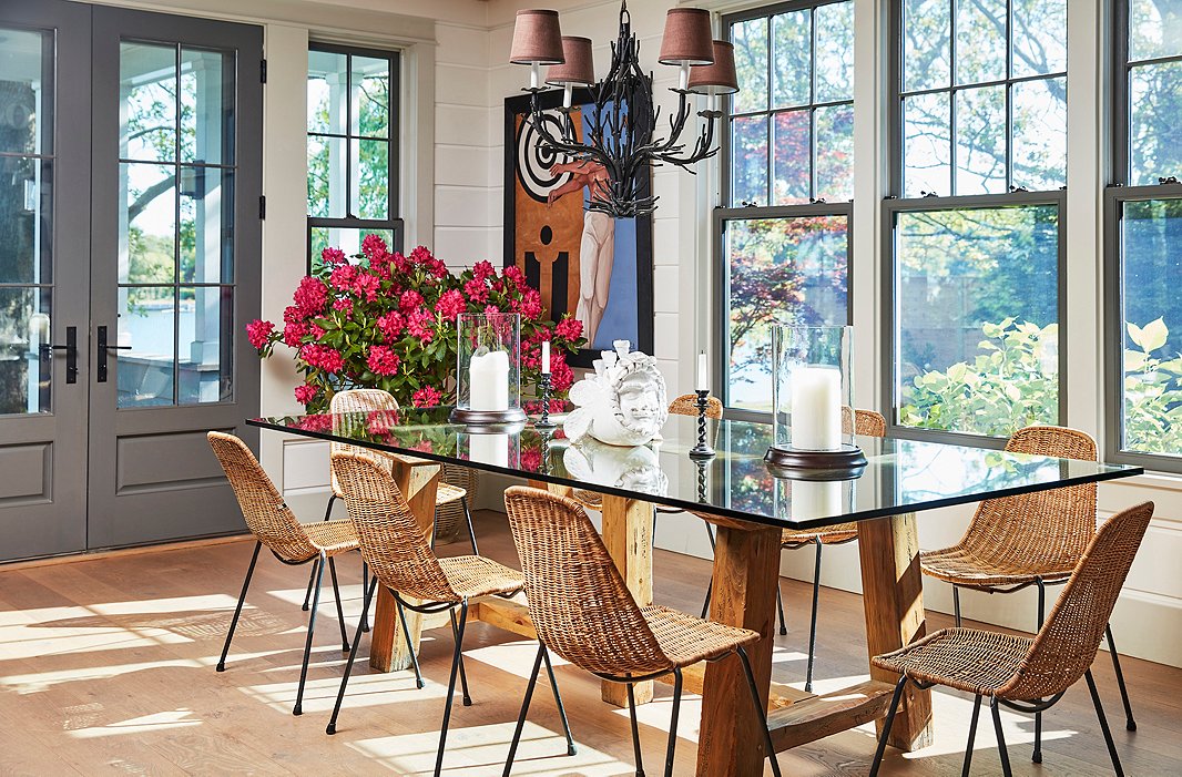 A chandelier from Laurin Copen Antiques in Bridgehampton hangs above a dining table crafted of reclaimed wood and glass. The set of midcentury wicker chairs was a lucky find from Paris’s Clignancourt flea market. 
