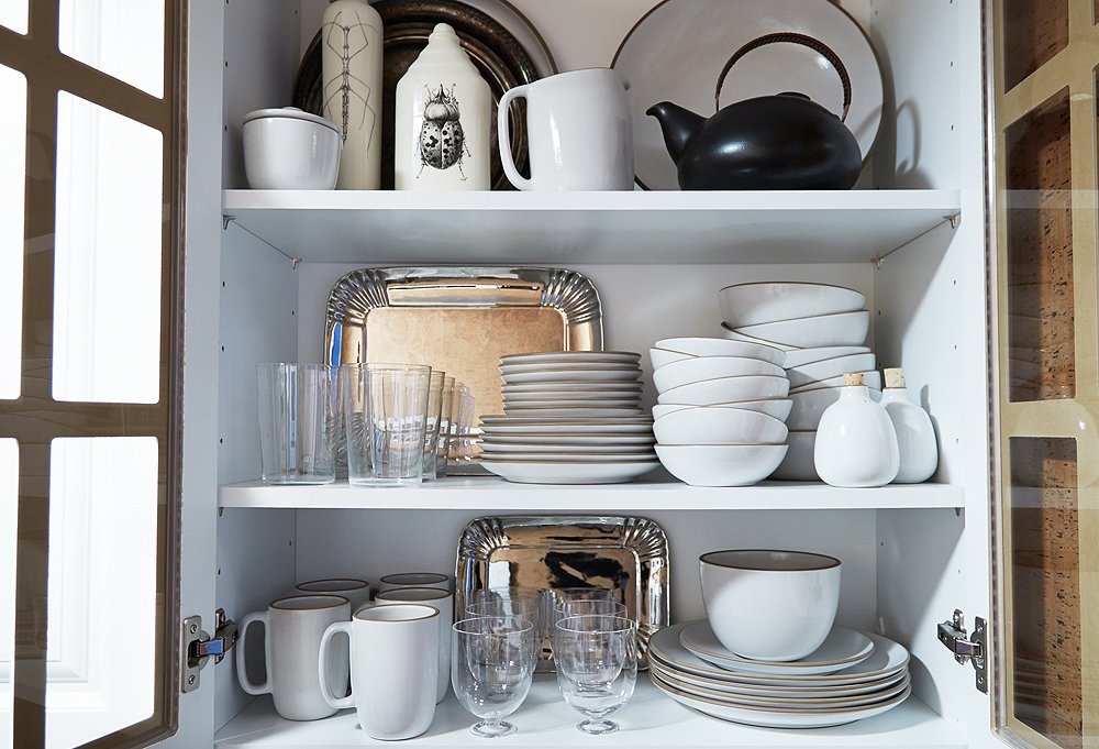 A glass-front kitchen cupboard brings to mind an old-fashioned butler’s pantry and is filled with Shawn’s everyday dishware.
