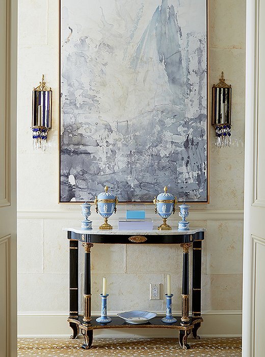 The front hall showcases Amanda’s intuitive touch for balancing old and new: A modern abstract by Ray Kass and flanking midcentury mirrored glass sconces command focus above a neoclassical-style console—“one of my first purchases,” says Amanda. The antelope carpet is by Stark.
