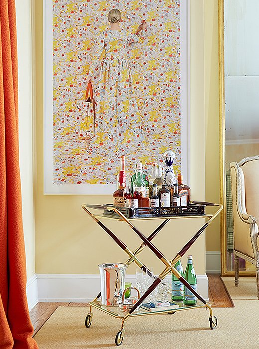 “I love that bar carts have come back into fashion,” says Amanda, whose rosewood-and-brass bar is always ready for cocktail hour in her living room. Equally intoxicating is a large-scale photo by Rachel Perry Welty.
