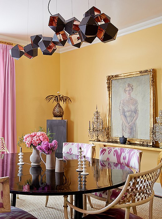 A steel-and-copper light fixture by Gabriel Scott hangs above a painting of Amanda’s maternal grandmother (“I like to think that she watches over all of my parties!”) and a black lacquered dining table surrounded with chairs she designed for Niermann Weeks.
