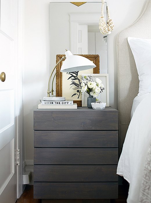 On her nightstand, a mix of feminine and crisp details reflects Caitlin’s style. An ivory-tone necklace by Joanna Williams, which Caitlin has had forever, adds extra style to the mirror.
