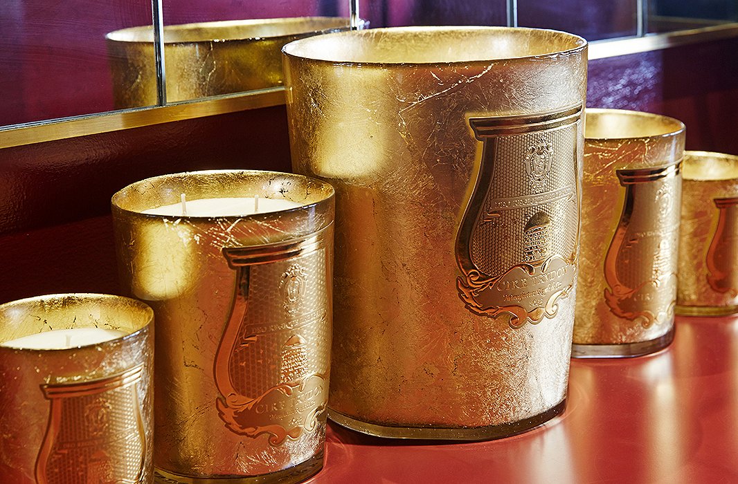 The gold-leaf vessels, handcrafted in Tuscany, are shaped like champagne buckets. Cire Trudon’s signature crest features a Latin inscription referencing the bees’ work for God and King Louis XIV.
