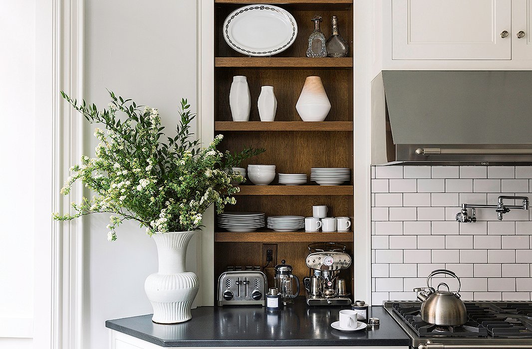 Nina kept all the shelving open to take advantage of the high ceilings while serving as gorgeous displays. Here, her collection of white Nymphenburg vessels and an Hermès platter complement the sculptural vase from Aero on the counter.
