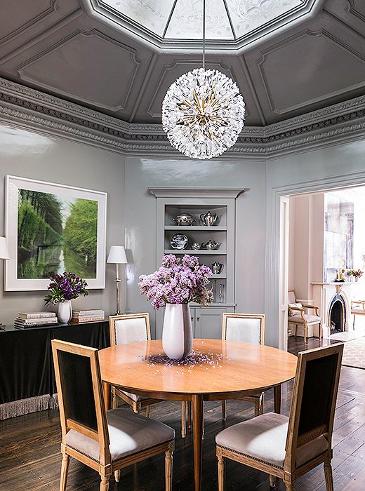 The formal dining room, with its beautiful 12-feet-high octagonal ceiling, is also the home’s grand entry. “We can fit 10 to 12 people in here,” says Nina of the leaf table. The high-gloss walls are painted with Farrow & Ball’s Lamp Room Gray. The Lynn Geesaman photo was Nina and her husband’s first art purchase together.
