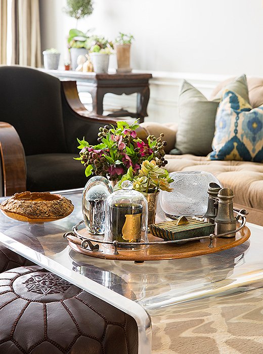 A sturdy acrylic waterfall coffee table is topped with favorite objects.
