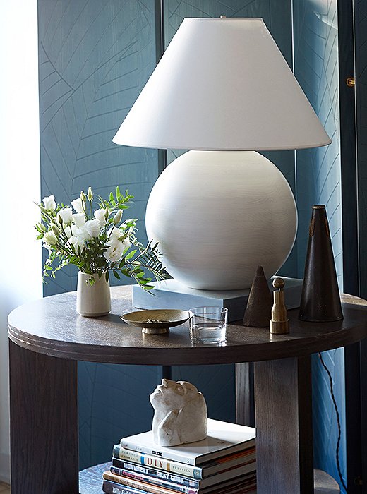 Samuel uses furnishings to heighten the effect of light, creating a poetic play. Here, a glowing white lamp on a geometric base sets off a painted folding screen made from palo blanco wood. Both pieces are his original design.
