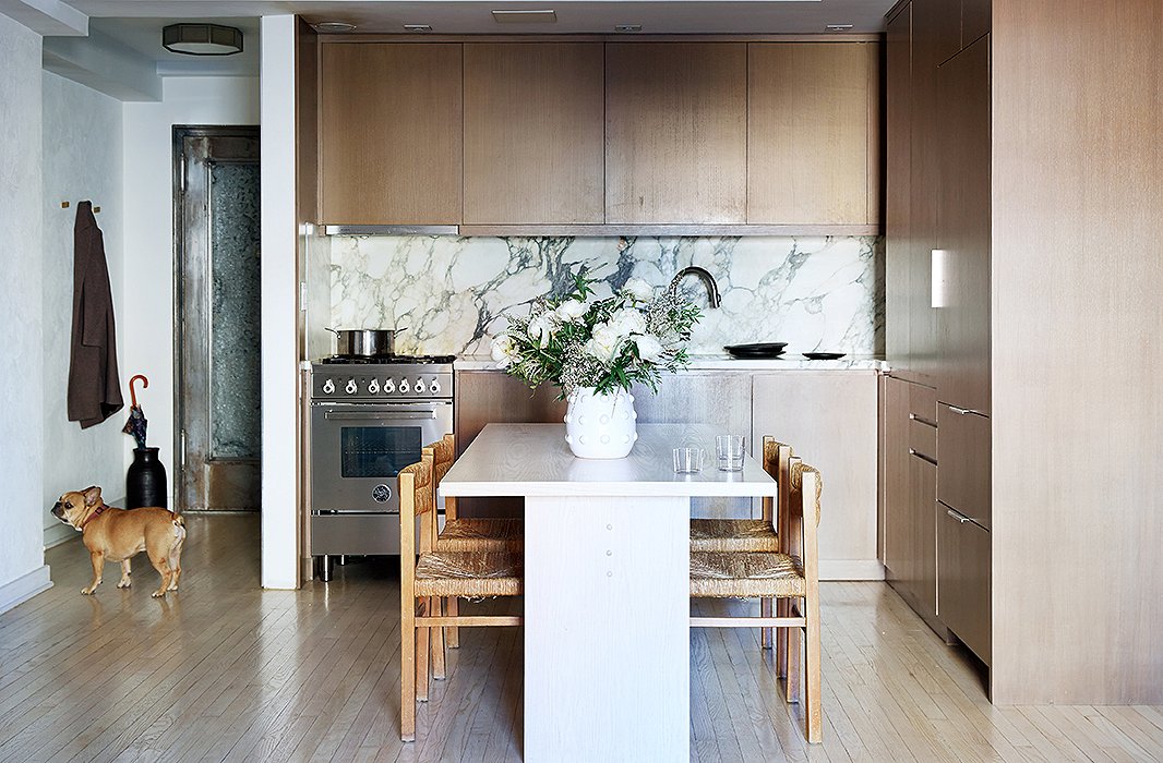 The Italian-marble kitchen backsplash, with its blown-up patterns, sets the gray palette of the apartment. Samuel cooks every day (unlike most New Yorkers), and when entertaining a crowd, he pulls the vintage dining chairs over to the sofa to seat 10 for dinner. 
