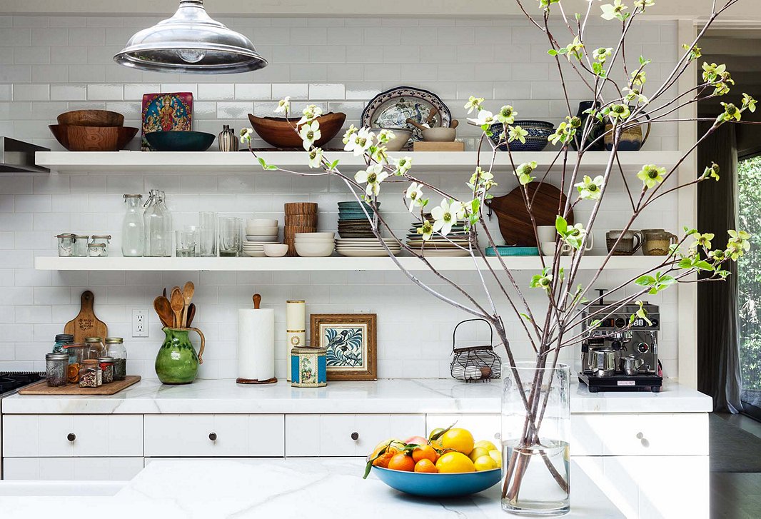 Subtle pops of color, an edited mix of dinnerware, and a spray of fresh tree branches help this kitchen embrace bohemian flair. Photo by Nicole LaMotte.
