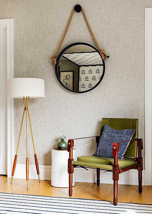 Opposite the patterned bed is a simple scene. The tripod floor lamp’s warm legs accents play well with the leather accents on the accompanying campaign chair. Find a similar mirror here.
