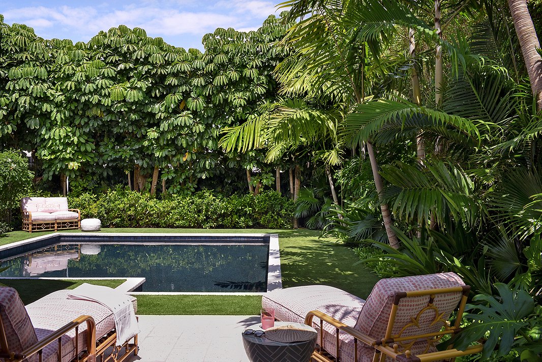 “Melanie really loved Celerie [Kemble’s] collection for Lane Venture,” says Caroline. In the backyard pool area, Caroline upholstered a few pieces from that collection in a poppy pink to stand out against the lush greens.  
