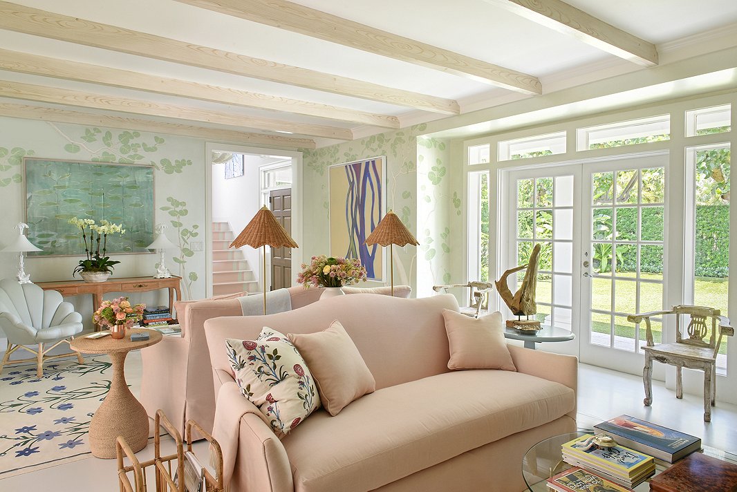 The mural on the living room walls was inspired by the family’s beach club. “We ran with it and made it her own,” says Caroline. She placed two blush sofas back-to-back to maximize the room’s long layout. Textures come alive in this space, with Caroline mixing jute with rattan with driftwood. (Find the rope-covered side table here.) The result is a room that feels classically coastal without being too beachy. 
