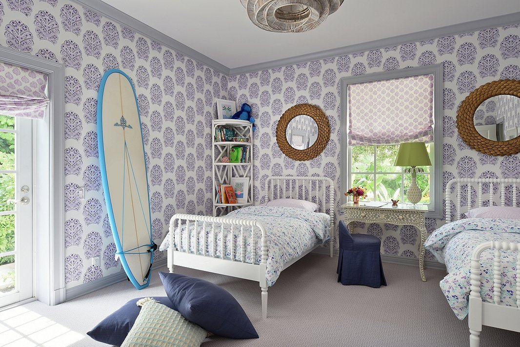 “I love this wallpaper,” Caroline says. The girls’ room is complete with two white spindle beds and an inlay table that doubles as a desk. 
