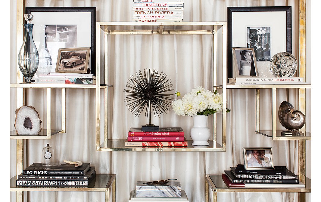 Each shelf is like a lesson on how to make a perfect vignette: Pile books by color, and perch one strong accent atop each stack.
