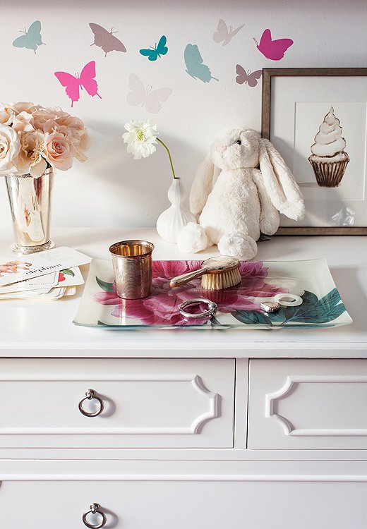 A vanity for the littlest lady of the house: a decoupaged John Derian tray holds Delphina’s little silver brush, while a cupcake illustration by Will Cotton leans against the dresser.
