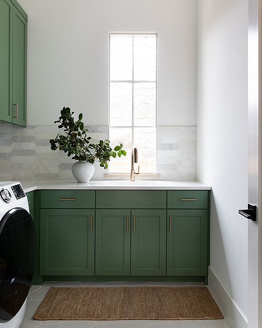 “I wanted a fun, cheery pop of color here,” says Christina of the laundry room. She painted the cabinetry a classic shade of Calke Green from Farrow & Ball. 
