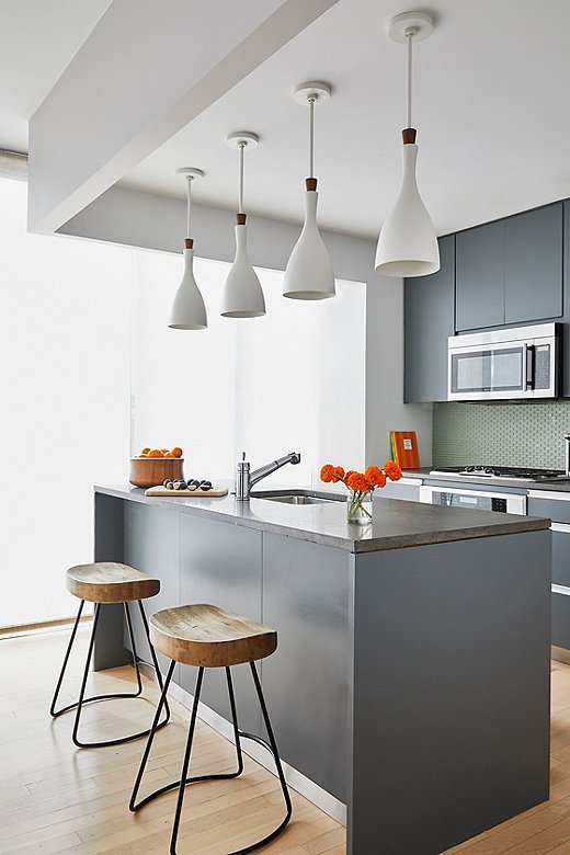 Modern white pendant lights add a nice curved shape to the kitchen vignette. Wooden counter stools bring some natural warmth.
