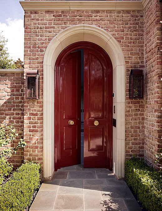 The arched front door, painted a not-so-subtle glossy wine red, gives just a hint at the maximalist interiors that lie beyond.

