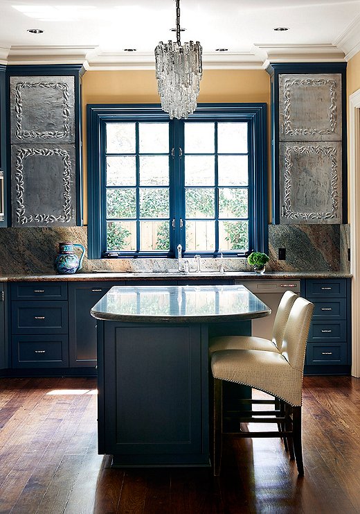 “We painted over all the stained cabinetry to give it a fresh look,” Dennis says. The multihue marble backsplash purposefully plays off the blue cabinetry.
