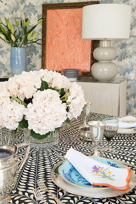 The formal dining room is full of pattern. Courtland extended that to her tabletop selection because she loves layering busy pattern on busy pattern. Here, she played off the room’s blue tint by adding Richard Ginori plates and topping them with colorful embroidered napkins.
