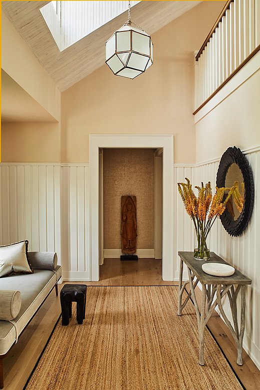 Soft colors and natural touches in the jute rug and wood table create an airy atmosphere in this hallway. Find a similar light fixture here.
