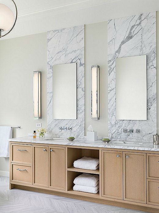 The homeowners wanted their master suite to be a sanctuary from the hustle and bustle of San Francisco. Heather extended the tonal look of the bedroom into the bathroom by using white Calacatta marble, light cabinetry, and chrome finishes. The herringbone flooring adds a subtle touch of texture.
