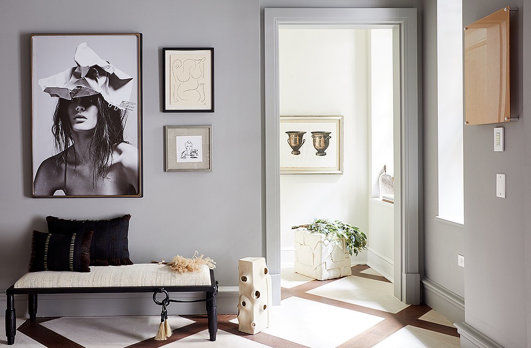 For the home's foyer, Gabriela Gargano of Grisoro Designs opted for a gallerylike space of art and fine furniture. Along one wall, an iron bench with a seat covered in woven horsehair rests beneath a fashionable black-and-white photograph. 