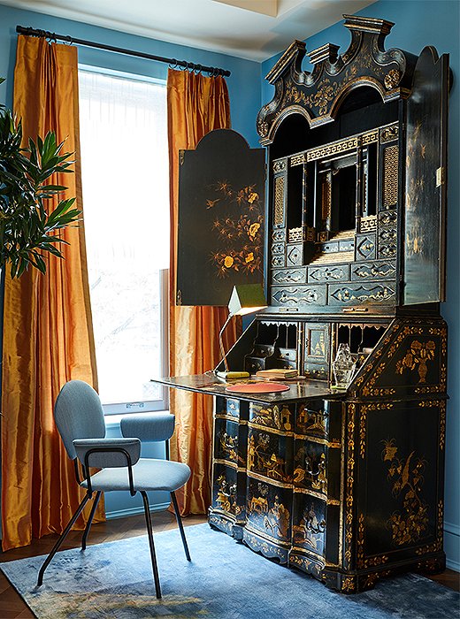 Inspired by the East, designer Perry Sayles sought to explore the aesthetic line between modernity and tradition. In this corner vignette, Perry mixed an antique Chinese secretary with a midcentury chair and a sleek task lamp. Orange taffeta draperies amplify the effect of natural light and bring warmth to the cool-tone space.

