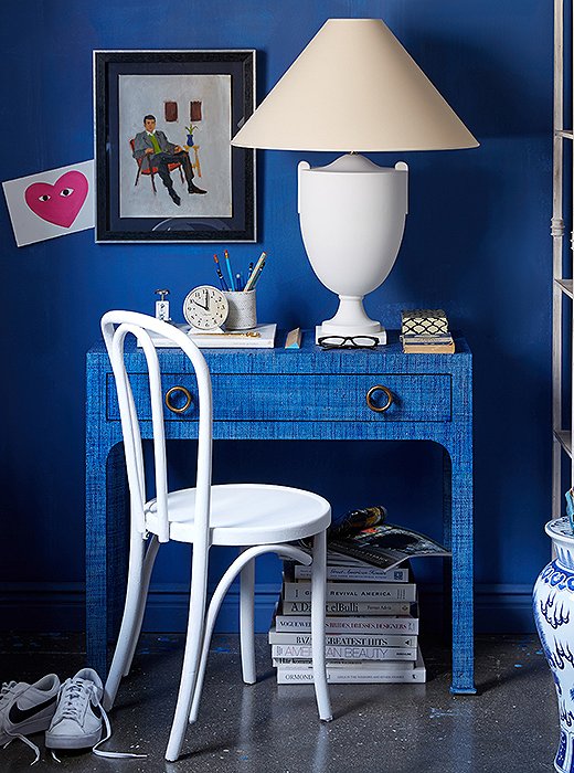 A deep-blue wall highlights the graceful silhouettes of the white lamp and the Thonet-style chair.
