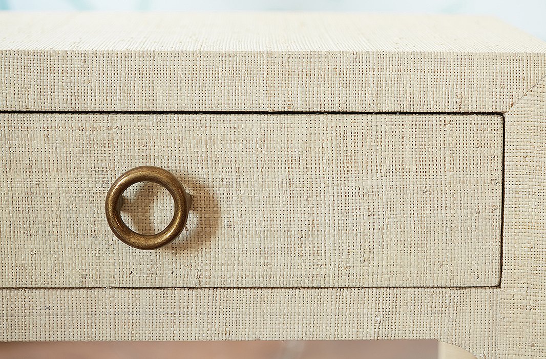 A brass-tone drawer pull adds modern contrast to an intricate raffia finish.
