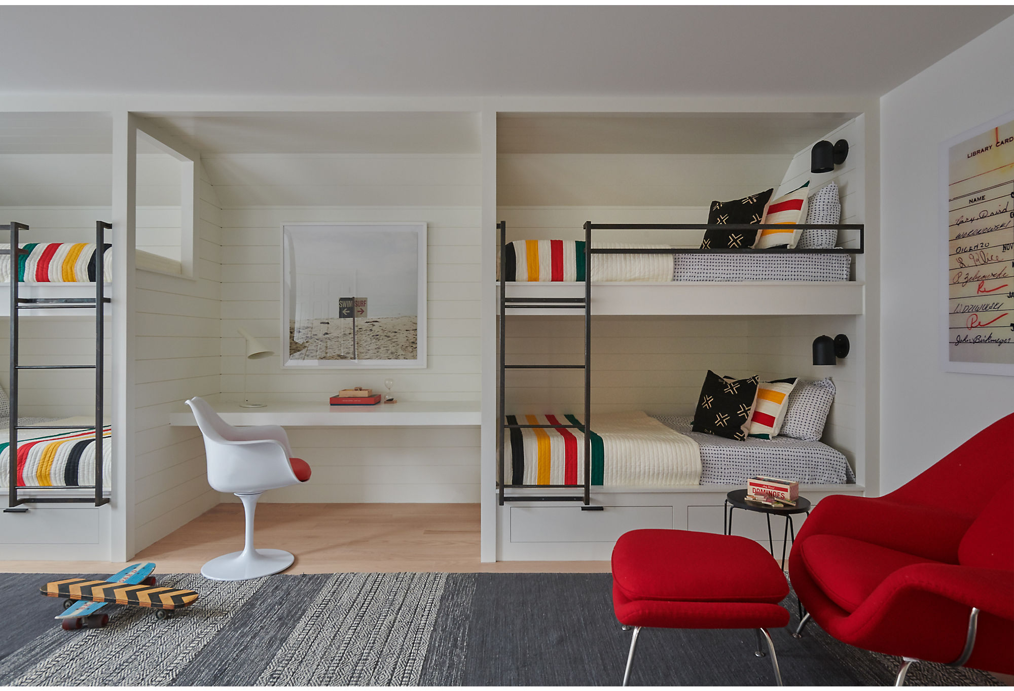The colorful bunk room leans a bit more modern than farmhouse with a red womb chair and beach photography. Find the framed photograph, Swim/Surf by Christine Flynn, here.
